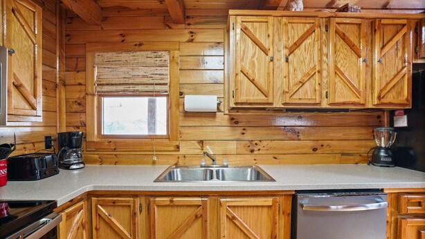 A kitchen with wooden cabinets, a stainless steel sink, a coffee maker, and a dishwasher. - White Oak Cabin | Hocking Hills, Hot Tub, Rec Room (Rockbridge)