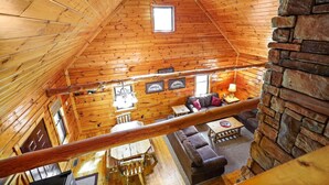 L’intérieur d’une cabane en rondins comprend une chambre à coucher située en mezzanine, une cheminée et un coin repas.