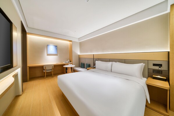 Una habitación de hotel con una cama grande, un escritorio, una silla, un televisor y una mesita de noche.
