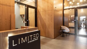A reception area with a wooden reception desk, a seating area, and a glass door leading to another room. -  Charlie Alves Guimarães Pinheiros (São Paulo)