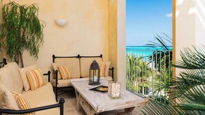 Un balcon avec vue sur la mer, agrémenté d’un ensemble de canapés, d’une lanterne et d’un porte-bougie en verre.