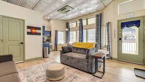 A spacious living room with a grey sofa, a patterned rug, and a small ottoman. - Keystone Lake Haven: Heated Pool & Ski Shuttle! (Keystone)