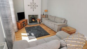 A living room with a grey sofa, a black rug, a fireplace, and a television.