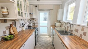 A kitchen with wooden countertops, white cabinets, a dishwasher, and a window providing a view.
