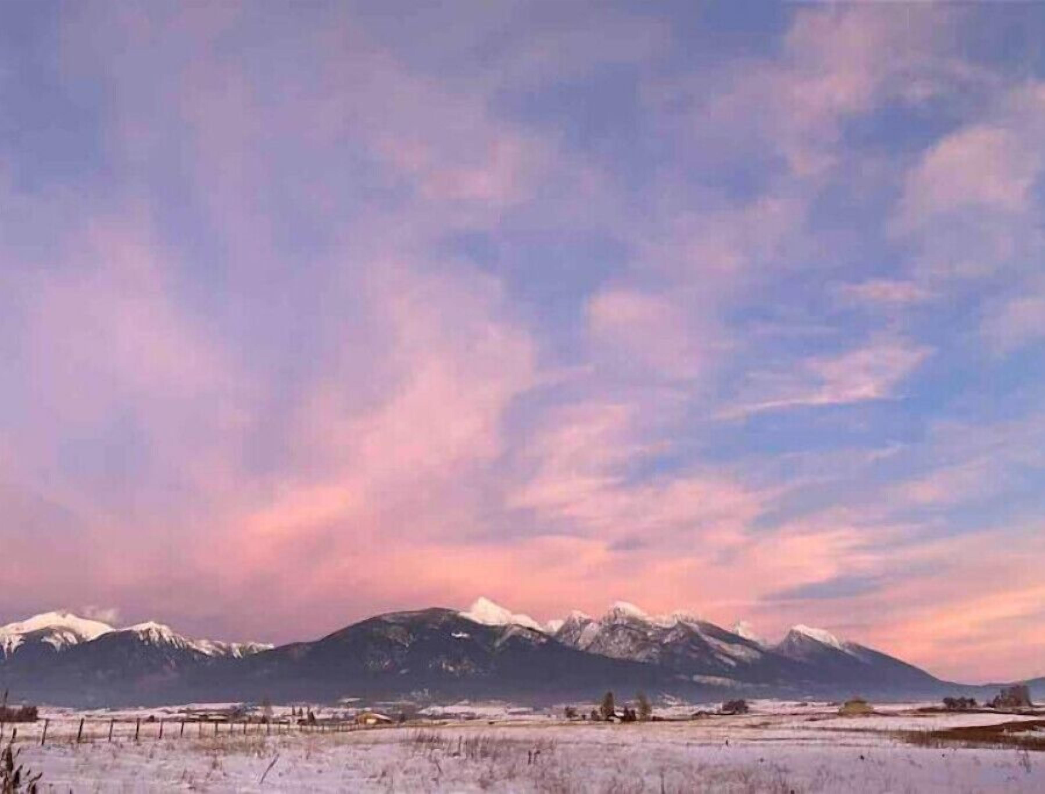 Un paisaje montañoso con picos nevados y cielo despejado.