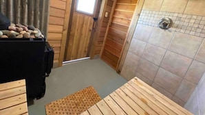 Une petite pièce en bois, équipée d’une douche, d’une fenêtre et d’un banc.