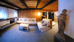 A modern living room with a wooden ceiling, a white sofa set, a small table, and a statue. - ATI Chalet-style apartment from the 1800s in the heart of Ortisei (Ortisei)