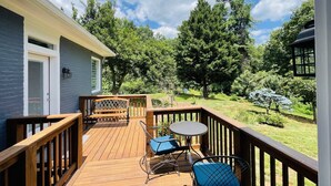 A wooden deck with a table and chairs, surrounded by a garden and trees. - Unit 2_Expansive Luxury Suite for up to 4 Persons (Charlottesville)