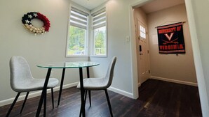 A dining area with a glass table and two chairs, a wreath on the wall, and a banner for the University of Virginia.
