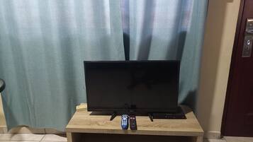 Un televisore su un supporto in legno, con telecomando, presa di corrente e una porta con serratura.