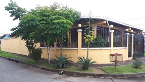 A yellow building with a curved roof, surrounded by greenery and a metal fence. - Balboa Village (Panamá)