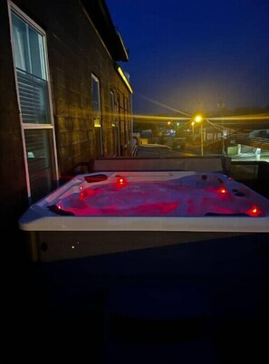 Een bubbelbad met uitzicht op een gebouw en straatverlichting 's nachts.