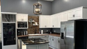A modern kitchen with white cabinets, a stainless steel refrigerator, and a central island.