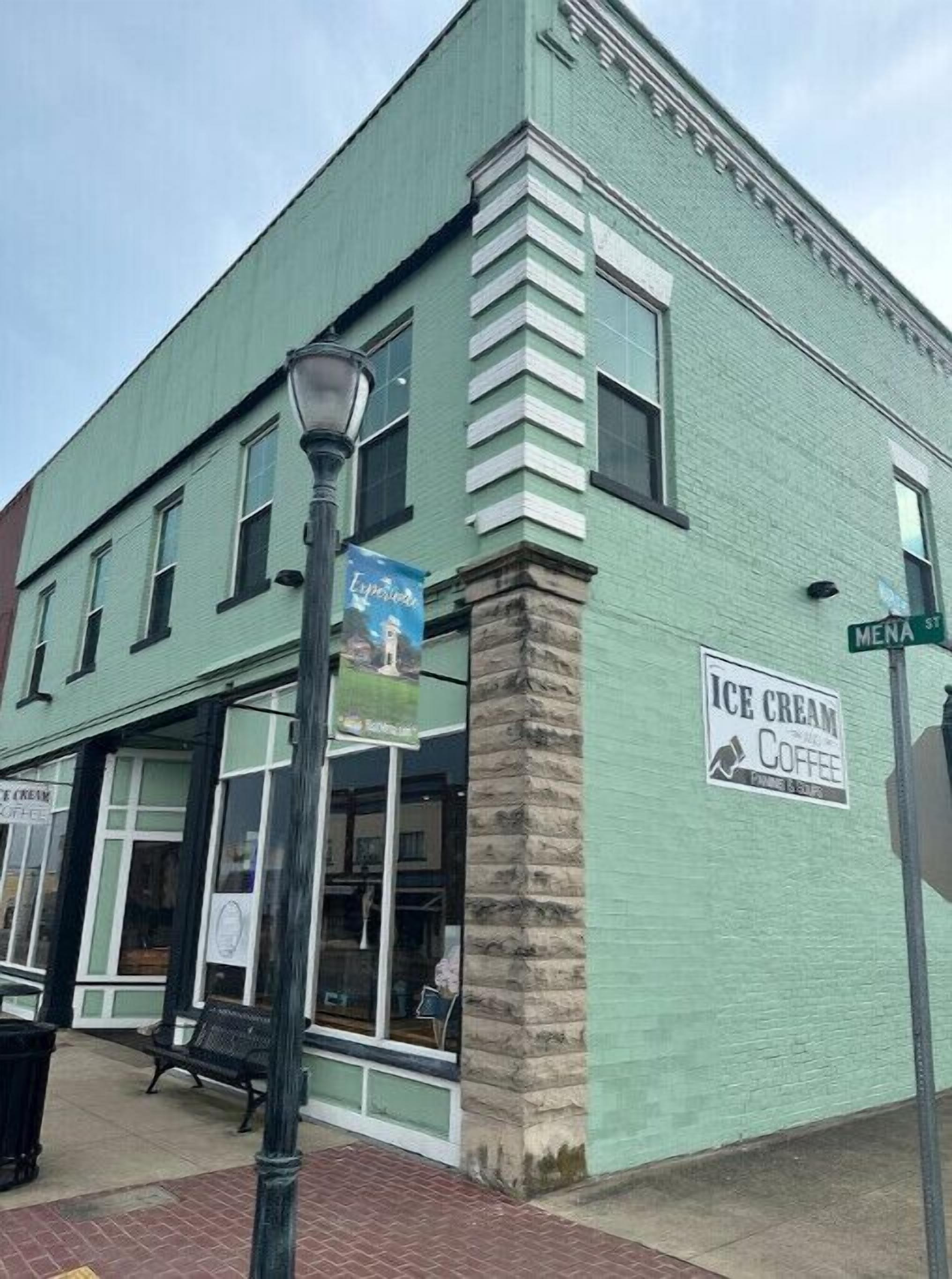 A green building with a sign for 'Ice Cream and Coffee' and a bench outside.