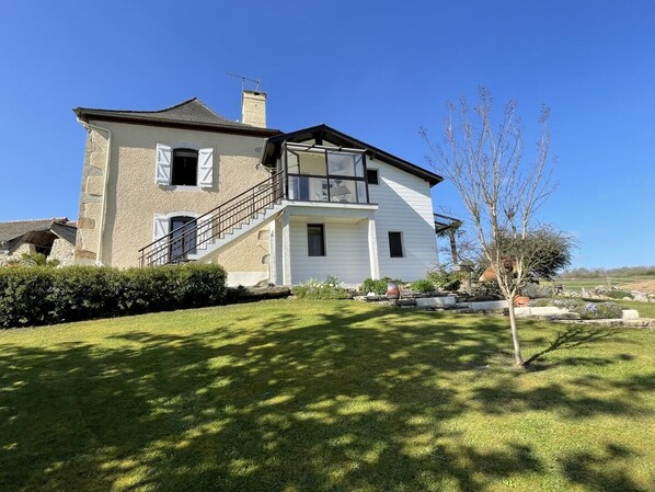 A two-story house with a balcony, a stone facade, and a well-maintained lawn. - CYRALIE - ASSON - Gîte (ASSON)