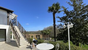 Une terrasse avec une table ronde et des chaises, un escalier et une vue sur le paysage environnant.