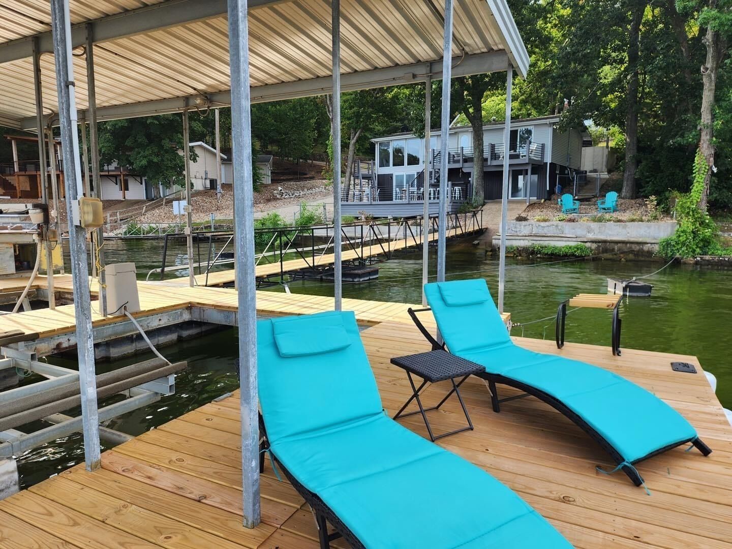 Una terraza de madera con dos sillones de descanso y un área cubierta.