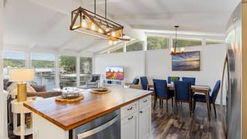 Une cuisine moderne avec un plan de travail en bois, des appareils en acier inoxydable et un coin repas comprenant des chaises bleues et une table.