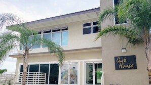 A two-story building with a sign reading "Club House." - Lofts 1B/R Lounge w/WiFi|Gym|near National Stadium (Kingston)
