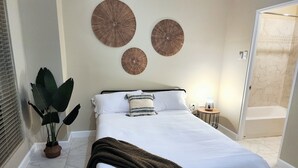 A neatly arranged bedroom with a bed, a bedside table with a lamp, and a potted plant. - Lofts 1B/R Lounge w/WiFi|Gym|near National Stadium (Kingston)