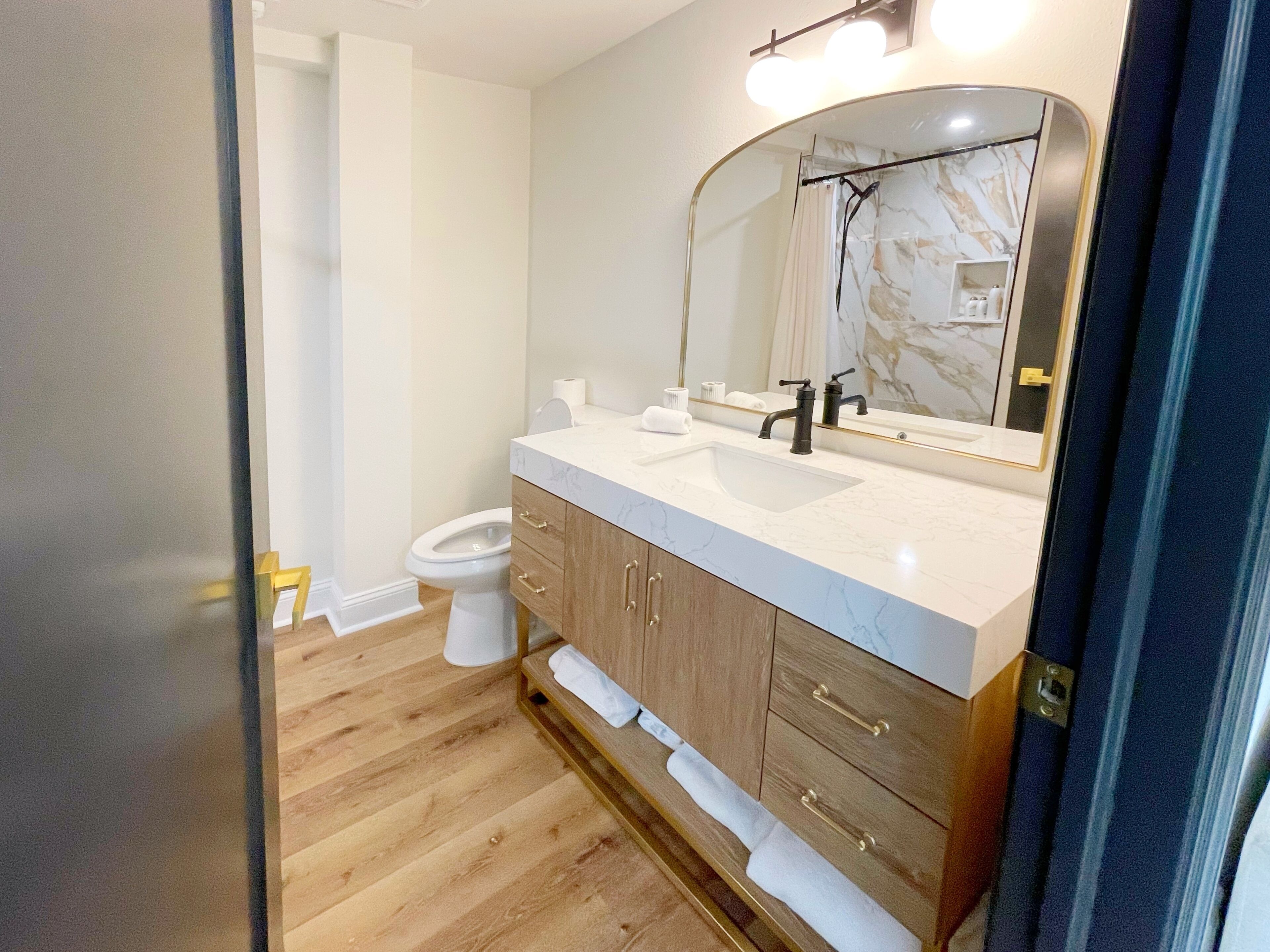 Une salle de bain moderne avec un lavabo en marbre blanc, des meubles en bois et un grand miroir.