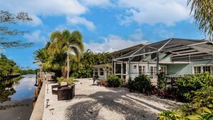 Une propriété située au bord de l’eau, dotée d’un patio couvert, d’un espace salon extérieur et offrant une vue sur l’eau.