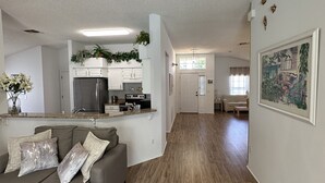 A modern living room with a grey sofa, wooden flooring, and a kitchen area in the background. - Private pool with a beautiful view overlooking the lake! Near Disney & Universal (Kissimmee)