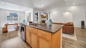 A modern kitchen with wooden cabinets, a granite countertop, and a built-in island. - New 2 level Twin Falls Home, 2 masters! (Twin Falls)