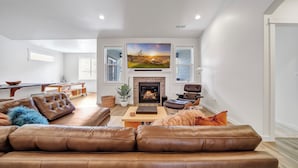 A spacious living room with a fireplace, leather sofas, and a large flat-screen TV. - New 2 level Twin Falls Home, 2 masters! (Twin Falls)