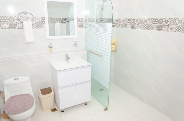 A modern bathroom with a white sink, toilet, and glass shower enclosure.
