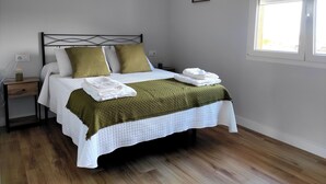 Un lit bien fait, avec un couvre-lit vert, du linge de lit blanc et une tête de lit.
