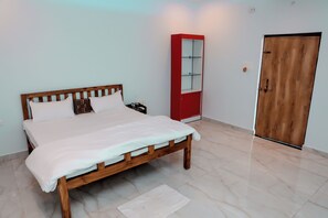 A bedroom with a wooden bed, a red wardrobe, and a wooden door. - The Restfo Pench Tiger Resort (Ramtek)