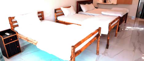 A hotel room with three wooden beds, a nightstand, a mirror, and a wardrobe.