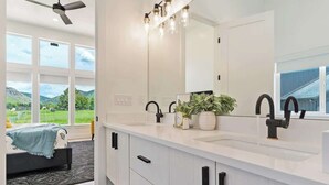 A modern bathroom with a large mirror, two sinks, and a potted plant. - Pickleball Playhouse, Hot Tub, Theater, Game Room! (Lava Hot Springs)