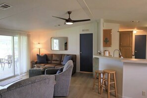 A modern living room with a sofa, a coffee table, and a dining area with stools. - Sunrise Retreat
 (Hernando)