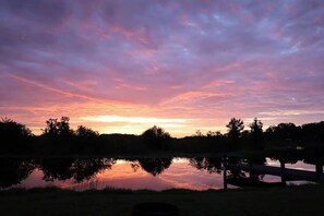 A sunset over a calm lake with a wooden fence in the foreground.