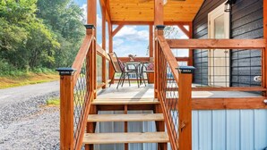 Eine Holzterrasse mit einer Treppe zu einem überdachten Bereich, der einen Tisch und Stühle sowie ein Metallgeländer umfasst.