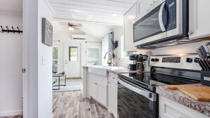 A modern kitchen with white cabinetry, a stainless steel oven, and a microwave. - Cozy Tiny Cabin Near Lake Guntersville (Guntersville)