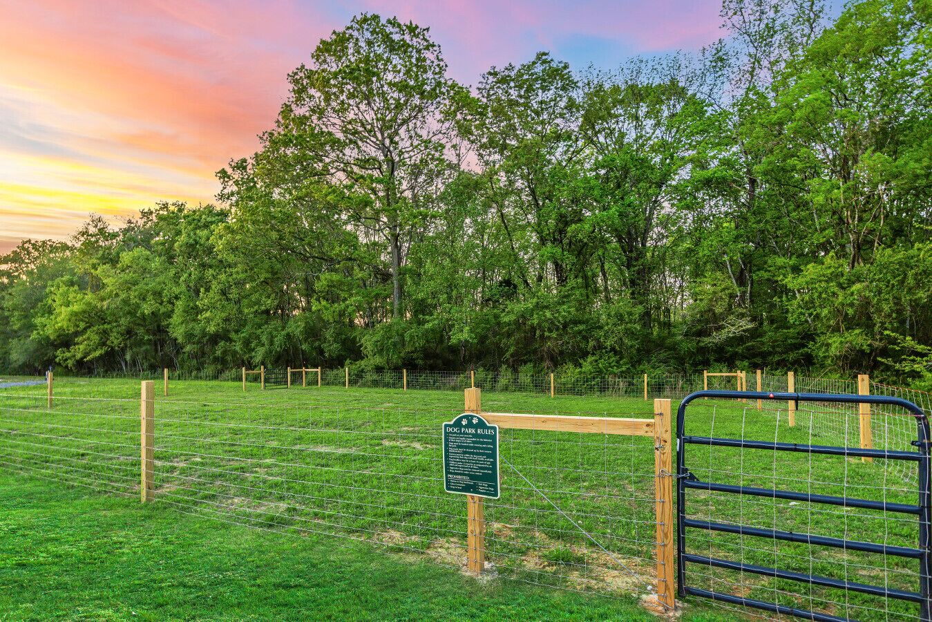 A fenced dog park with a sign detailing rules.
