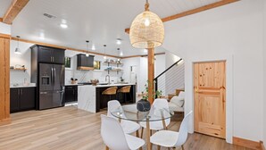 A modern kitchen with dark cabinets, a stainless steel refrigerator, and a marble countertop. - Mojave in the Pines - New Luxury Cabin in Hochatown Sleeps 4 (Broken Bow)