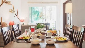Un coin repas avec une table mise pour le petit-déjeuner, des chaises, un ventilateur de plafond et une fenêtre donnant sur un paysage verdoyant.