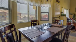 Un comedor con mesa de madera, sillas y una lámpara de araña.