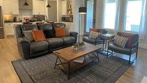A modern living room with a leather sofa, a wooden coffee table, and a dining area with a small table and chairs.