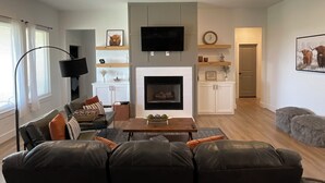 A modern living room with a fireplace, a flat-screen TV, and a sofa.