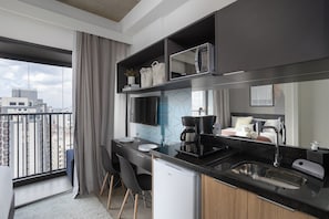 A modern kitchen with a large window, a built-in coffee machine, and a compact refrigerator.