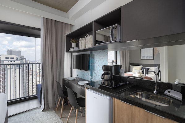 A modern kitchen with a large window, a built-in coffee machine, and a compact refrigerator.