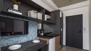 Una cocina moderna con comedor, una cafetera y un refrigerador pequeño.