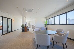 Una sala de conferencias moderna con una mesa redonda, varias sillas y una planta en maceta.
