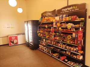 A grocery store interior with shelves stocked with various products, a refrigerator, and a freezer.