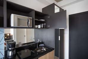 A modern kitchen with a built-in microwave, coffee maker, and stainless steel sink.